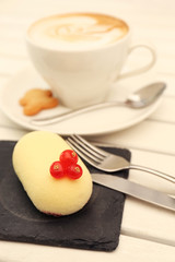Dessert with red currant and cappuccino on light wooden table