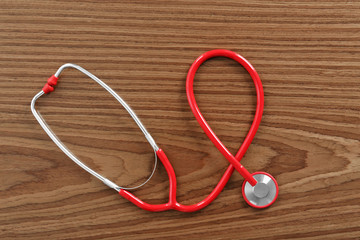 Red stethoscope on wooden table
