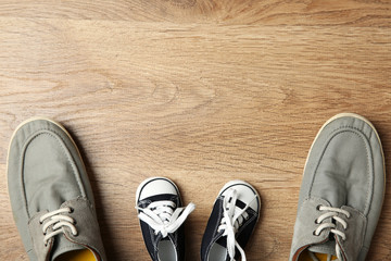 Big and small shoes on wooden background