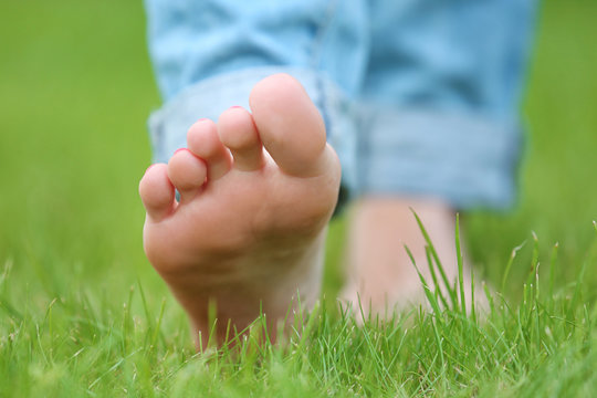 Woman walking barefoot  on green grass background