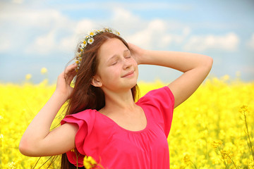 Sweet girl in meadow with wild spring flowers