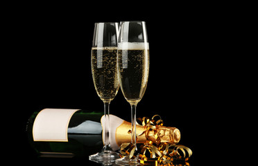 Two champagne glasses and bottle on black background
