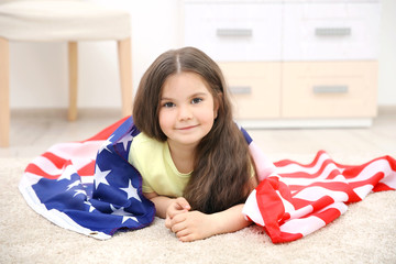 Cute little girl and American flag in room
