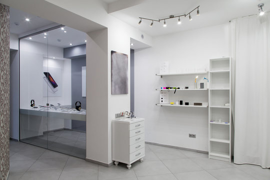 Digital technology shop interior in white tones, rack and shelves behind the showcase