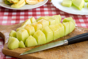 Sliced melon on the kitchen wooden board and kitchen knife