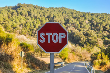 Stop sign in the background of beautiful landscape and road.