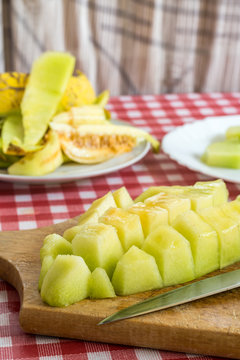 Sliced melon on the kitchen wooden board and kitchen knife