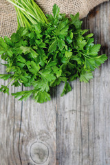 Obraz na płótnie Canvas Fresh parsley on a wooden background and jute bags