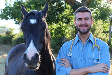Handsome male vet smiling close to a horse 