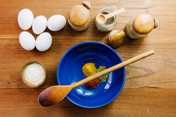 Blue bowl with spices, spices racks, wooden spoon, eggs and dehy