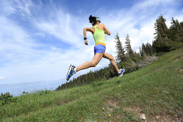 Obraz premium healthy young woman trail runner running on beautiful mountain peak