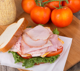 Delicious Ham Sandwich With Tomatoes and Mustard in Background