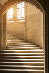 Light shining through windows onto stone stairs stairway staircase under a gothic archway. Ivy league college university architecture future ambition opportunity potential success concept.