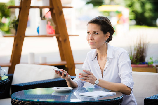 Portrait of a businesswoman using smart phone in sidewalk cafe.