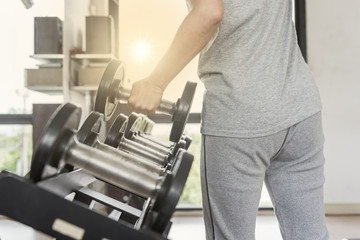 Strong woman's hand takes a heavy dumbbell in gym