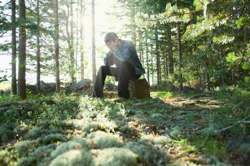 Sad young man sits in wood on stone
