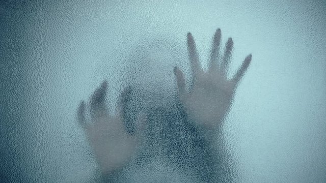female hand and head, spooky shadows on the glass wall, in full HD, Horror movie scene