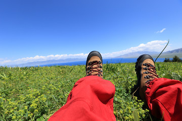 hiker sitting on a grass mountain top with first person perspective view