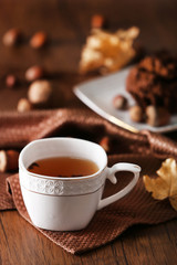 Cup of tea with autumn decor on wooden table.