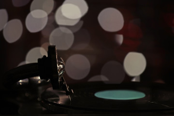 Turntable with vinyl record on dark blurred background