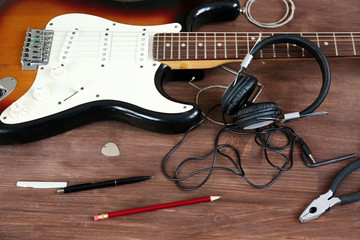 Naklejka premium Guitar with headphones on wooden surface closeup