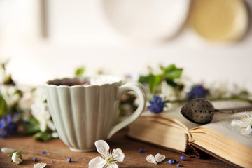 Open book and cup of tea  on wooden table