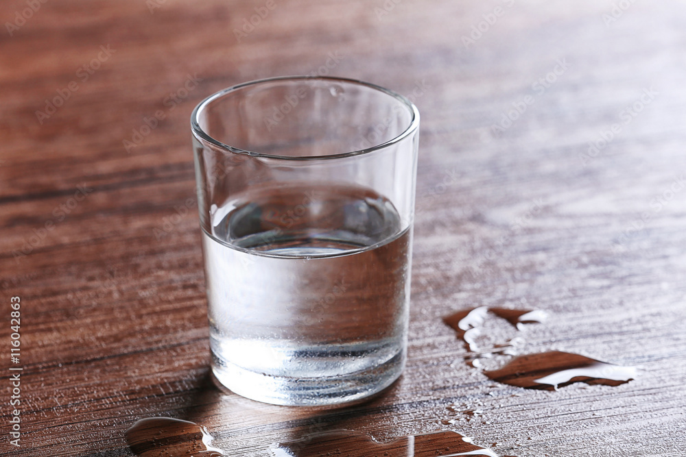 Wall mural Filled glass of water on wooden background