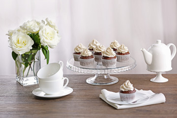 Tasty cupcakes with roses on stand