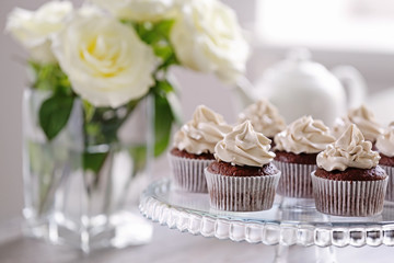 Tasty cupcakes with roses on stand