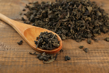 Dry tea leaves with spoon on wooden table