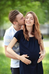 Fototapeta premium Happy family expecting baby on green nature background