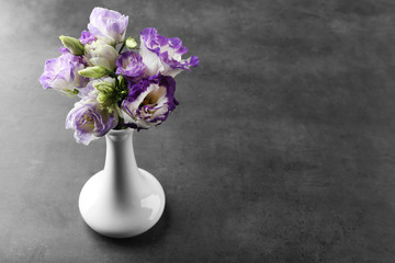 Beautiful flowers in vase on grey background