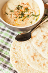 A bowl of creamy hummus with olive oil and pita chips.