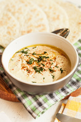 A bowl of creamy hummus with olive oil and pita chips.