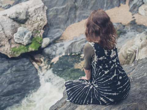 Woman sitting on rocks by creek