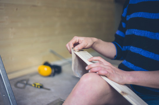 Young woman sanding cladding