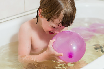 boy bathes in a bathroom with balloons