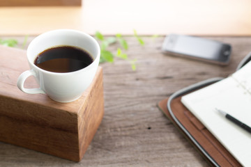 Fototapeta na wymiar white cup coffee with note book smart phone on wooden top table