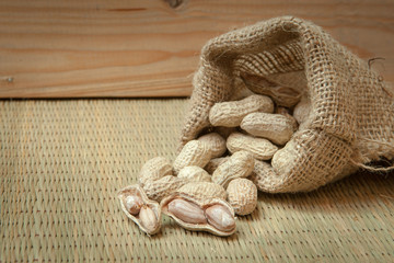 peanuts in sack on bamboo mats and wood background