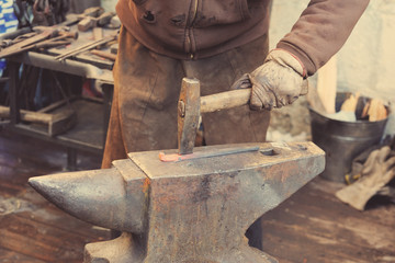 Blacksmith working metal with hammer on the anvil