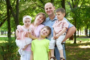 Fototapeta premium happy family portrait on outdoor, group of five people posing in city park, summer season, child and parent