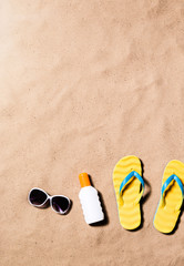 Naklejka premium Flip flop sandals, sunglasses and sunscreen, sand beach