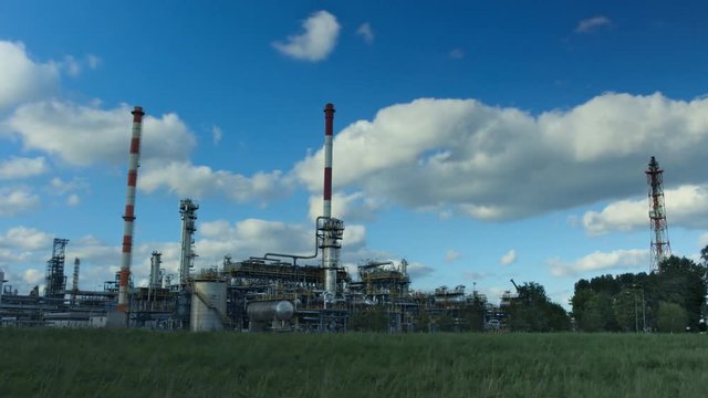 Time lapse oil refinery in sunny weather with clouds in background