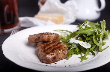 Steak with arugula salad on dark background