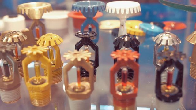 A wide range of fire sprinklers, different colors and sizes, on the glass shelf