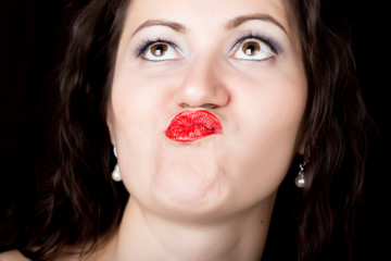 Close-up woman looks straight into the camera on a black background. expresses different emotions, sending a kiss