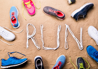 Running shoes and run sign made of shoelaces, sand