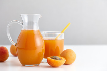 Fototapeta na wymiar Ripe apricots and a glass jug with fresh juice