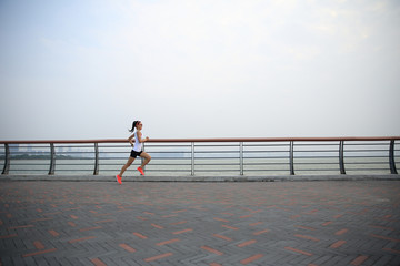 young fitness woman runner running on seaside