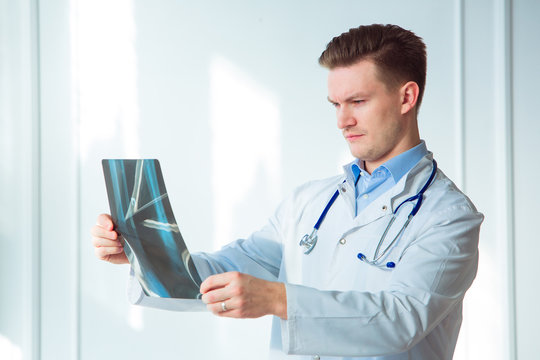 Portrait of young male doctor looking at x-ray